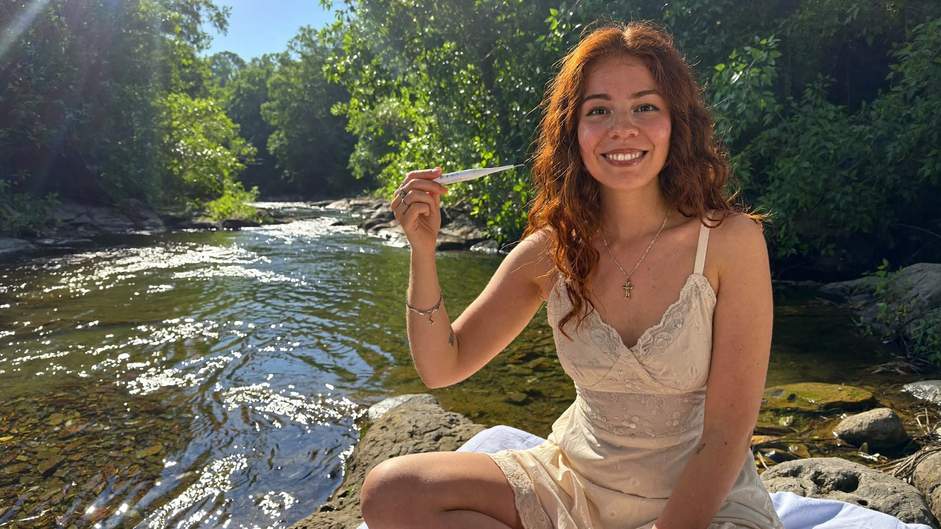 Ayleen junto al río sosteniendo un termómetro basal